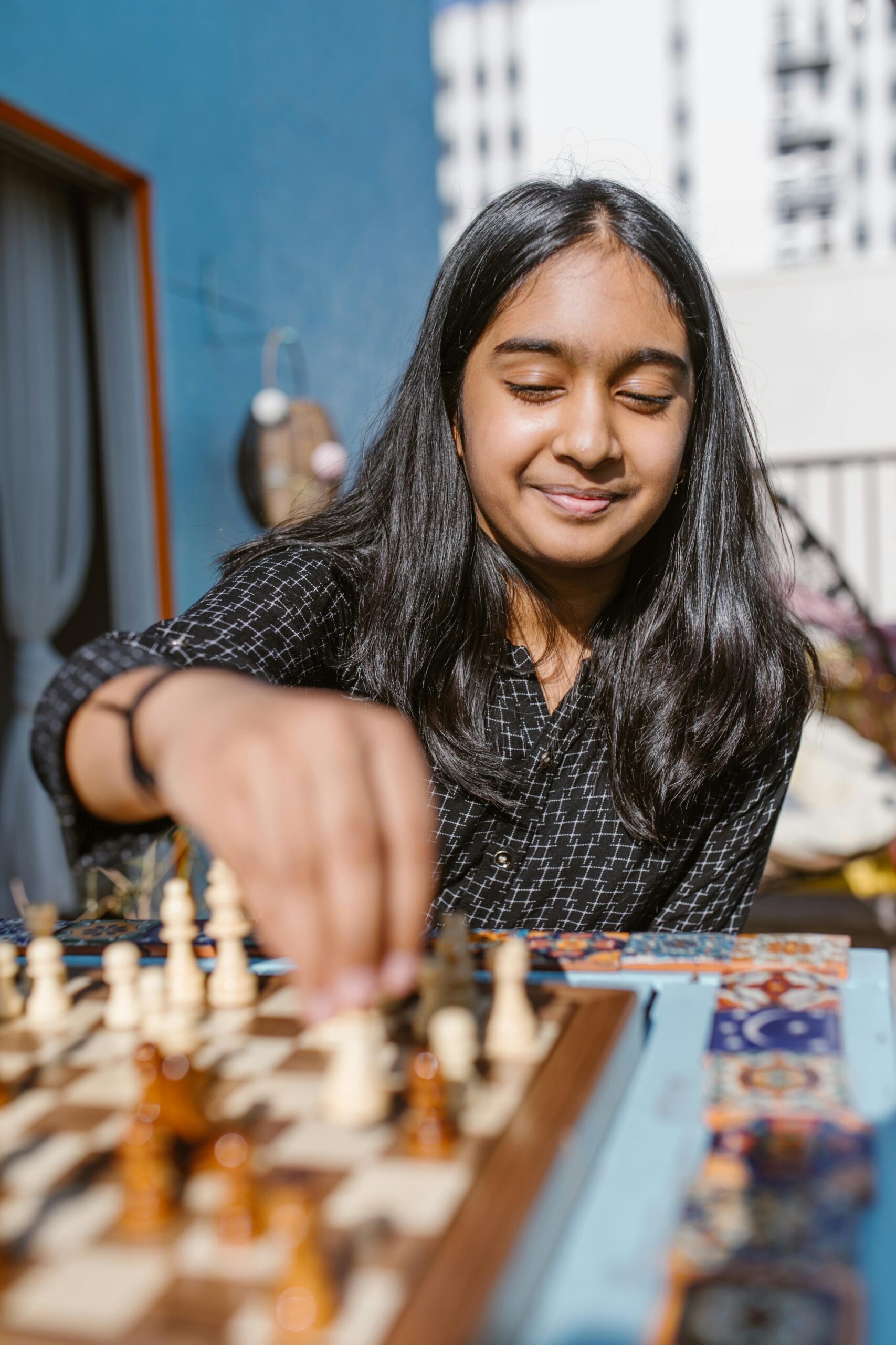 Young girl happily playing chess on a sunny day, focusing intently on the game.